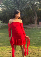 Woman in a red off-shoulder ruffle dress standing on grass outdoors