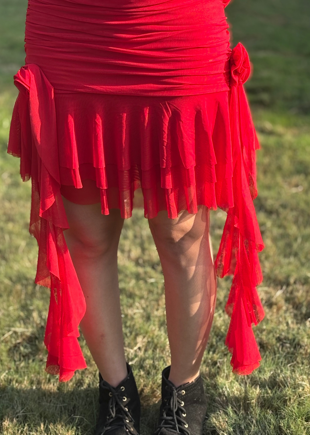 Red ruffled asymmetrical skirt with side bows, worn outdoors on grass