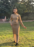Woman in long-sleeve beige fitted maxi dress standing on grass in outdoor garden