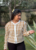 Woman outdoors in a textured striped cardigan with ruffled trim and black pants