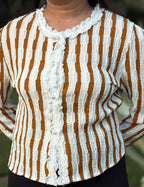 Woman wearing textured long sleeve top with white and brown vertical stripes and lace trim