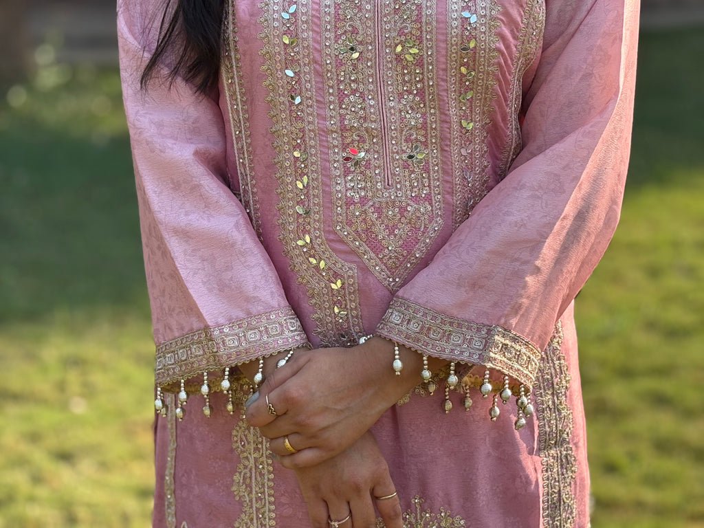 Woman wearing pink embroidered kurta with mirror work and pearl details, outdoor setting