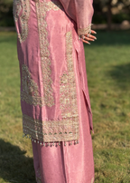 Pink embroidered traditional outfit with gold detailing and beadwork, outdoor setting