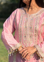 Woman wearing a pink embroidered kurta with gold sequin detailing and beaded cuffs outdoors